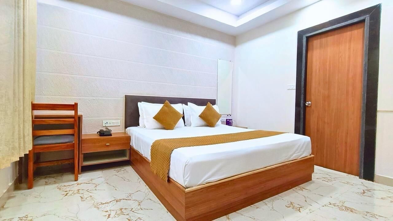 A hotel room with a wooden bed, a nightstand, a chair, and a door.