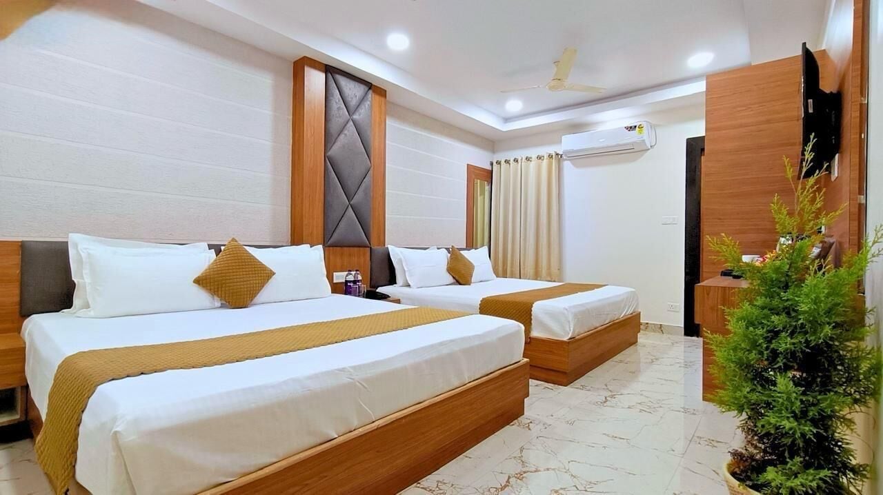 Habitación de hotel con dos camas, un televisor, una planta pequeña y un ventilador de techo.