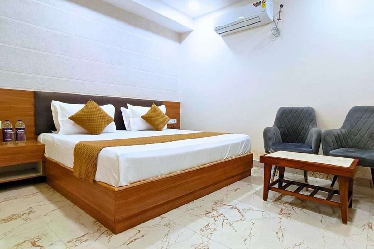 A hotel room with a bed, two armchairs, a small table, and a minibar.