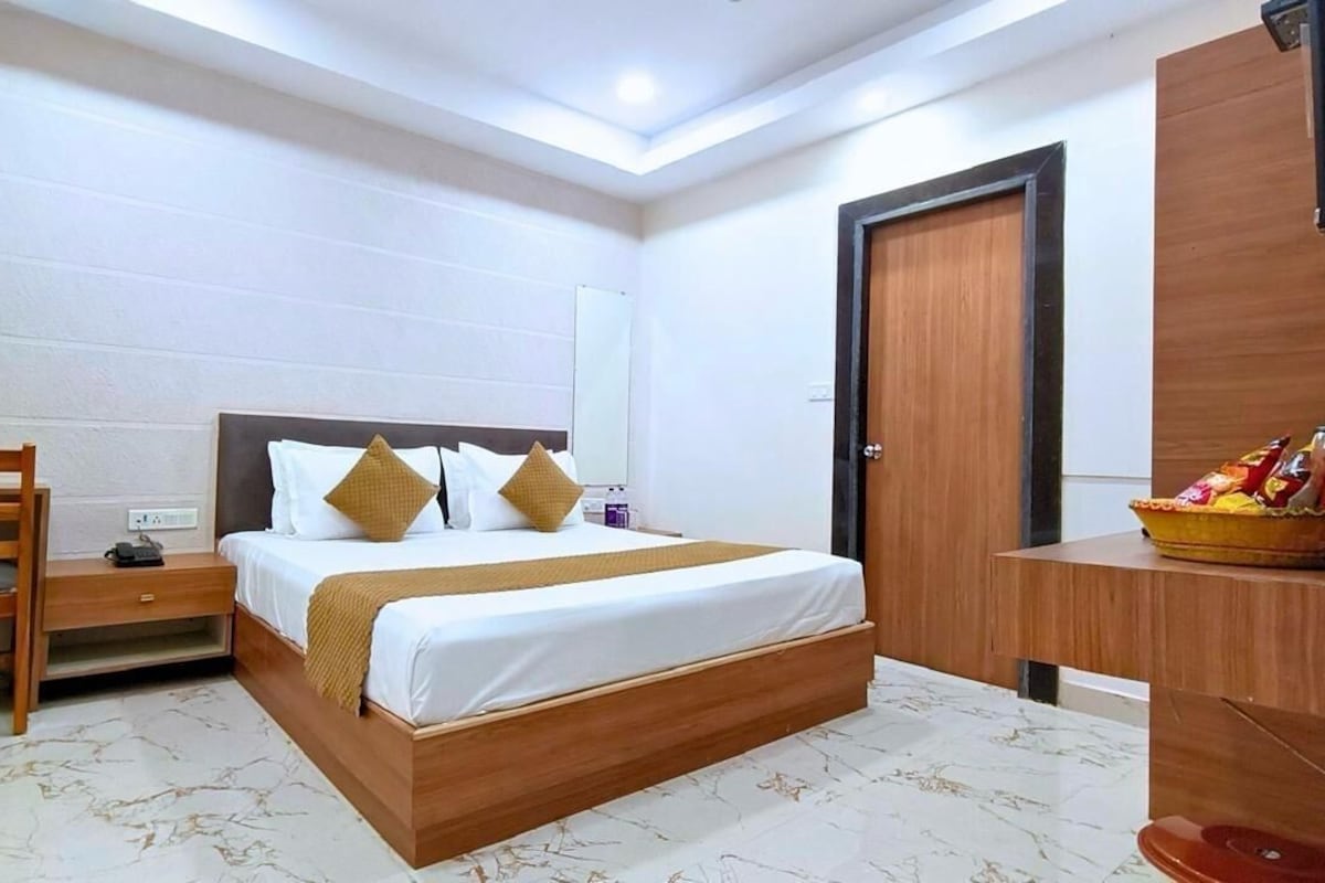 A hotel room with a wooden bed, a nightstand, a desk, and a mirror.
