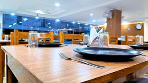 Ein Restaurant mit Holztischen, Stühlen und einem schwarzen Teller mit einer Gabel auf einem Tisch.