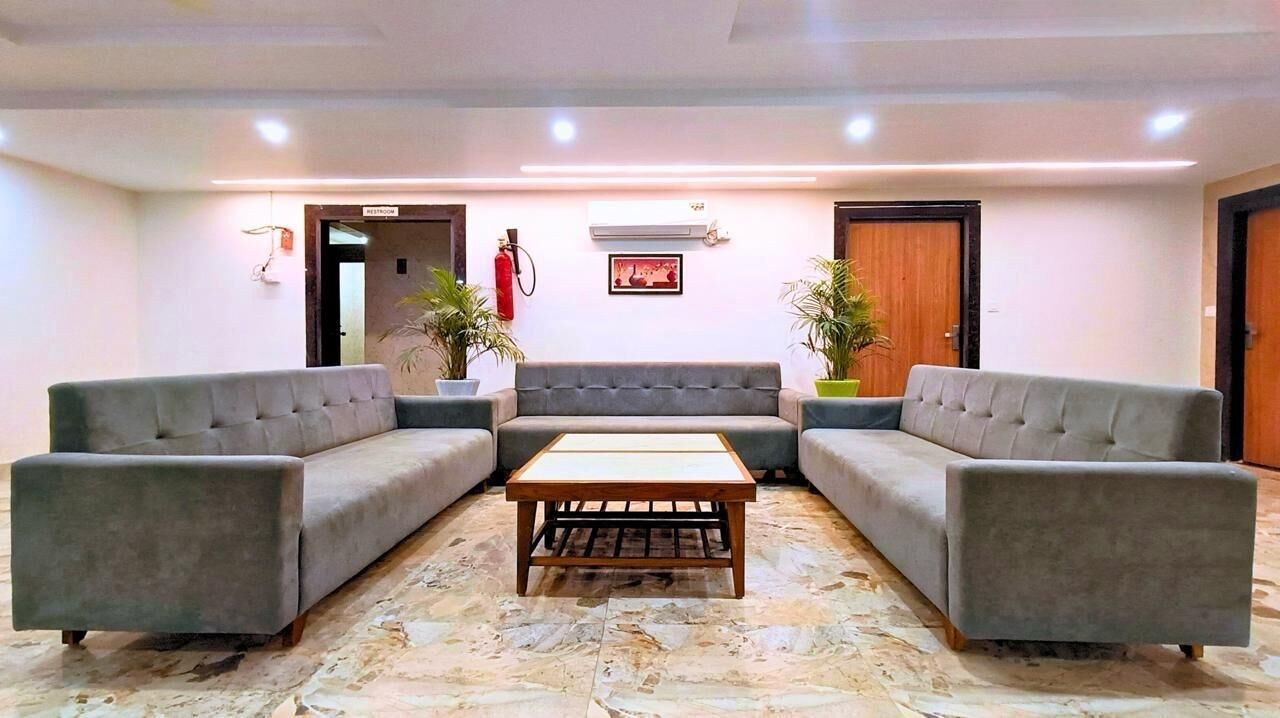 A reception area with two grey sofas, a wooden coffee table, and potted plants.