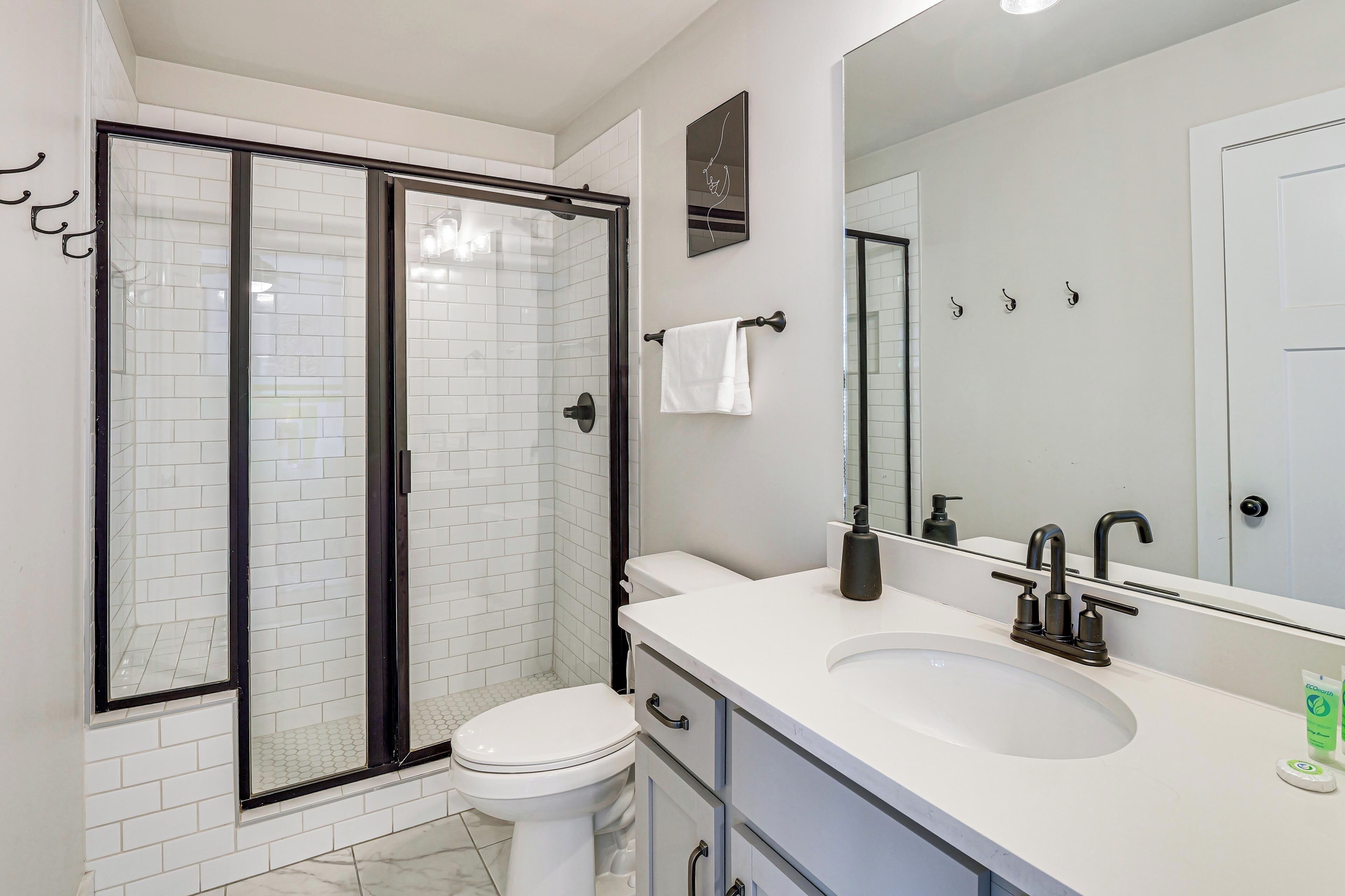 A modern bathroom with a glass-enclosed shower, a white toilet, a sink with a mirror, and a towel rack.