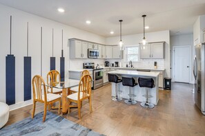 A modern kitchen with a central island, bar stools, wooden chairs, and a dining table. - 6 Mi to Broadway: Nashville Townhome w/ Balcony! (Nashville)
