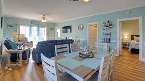 A spacious living area with a dining table, blue sofa, and a ceiling fan. - < 5 Mi to Private Beach Access! Myrtle Beach Condo (Myrtle Beach)