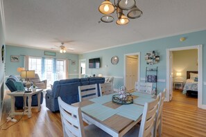 A spacious living area with a dining table, blue sofa, and a ceiling fan. - < 5 Mi to Private Beach Access! Myrtle Beach Condo (Myrtle Beach)