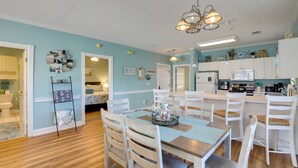 A spacious kitchen with white cabinets, a microwave, and a coffee maker. There is a dining area with a wooden table and white chairs. - < 5 Mi to Private Beach Access! Myrtle Beach Condo (Myrtle Beach)
