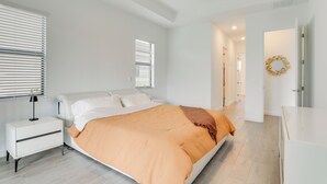 Een moderne slaapkamer met een bed, nachtkastje en een gang naar een andere kamer.