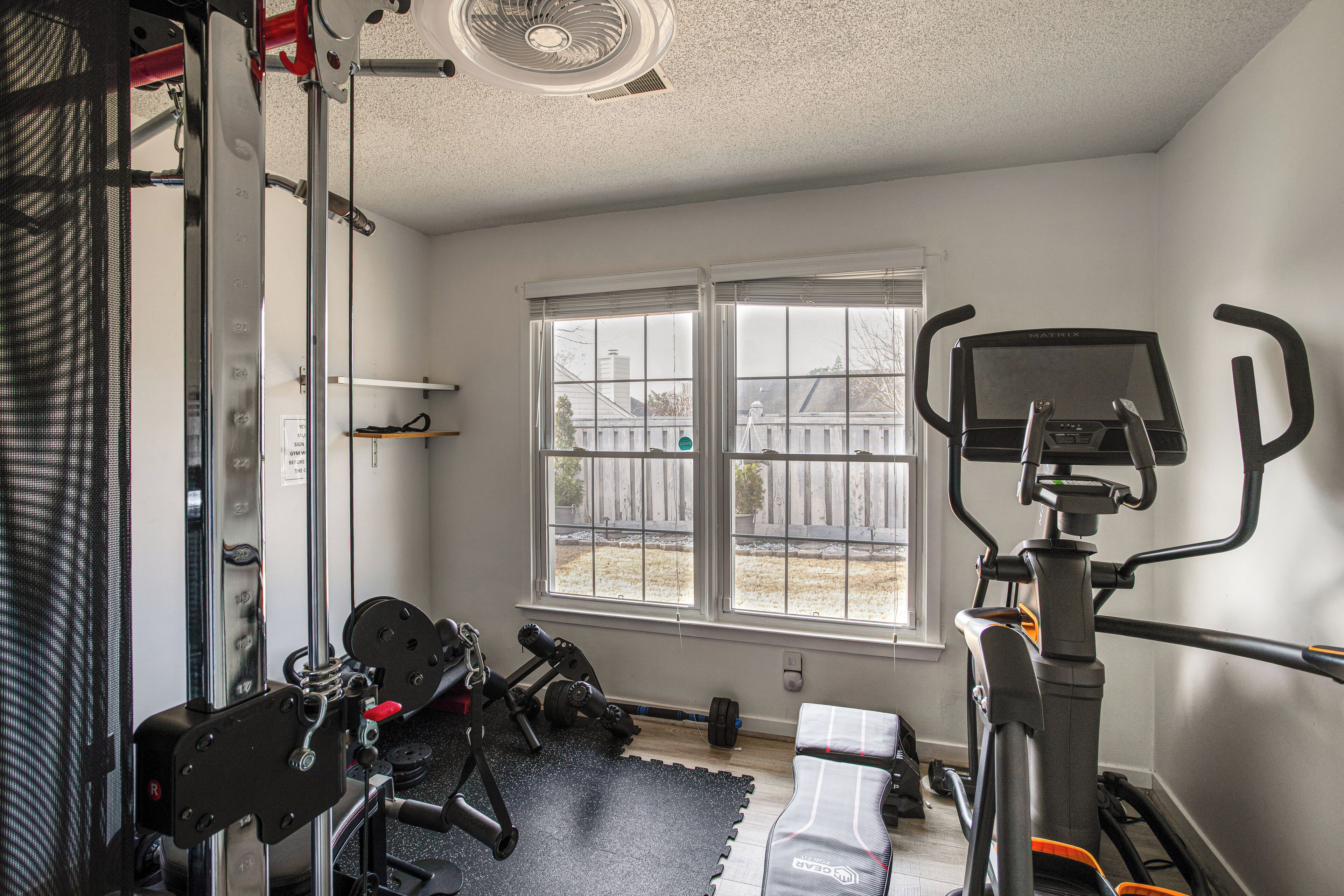 A home gym with a treadmill, weight bench, and various exercise equipment.