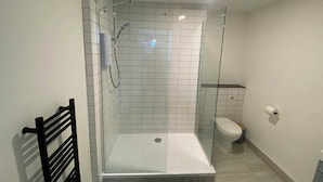 Une salle de bain moderne avec une douche à parois de verre, des toilettes blanches et un porte-serviettes noir.