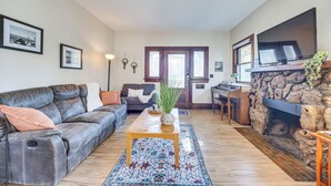 A living room with a leather sofa, a wooden coffee table, a fireplace, and a television mounted on the wall. - Walk to Colorado College & Dwtn! Home w/ Patio (Colorado Springs)