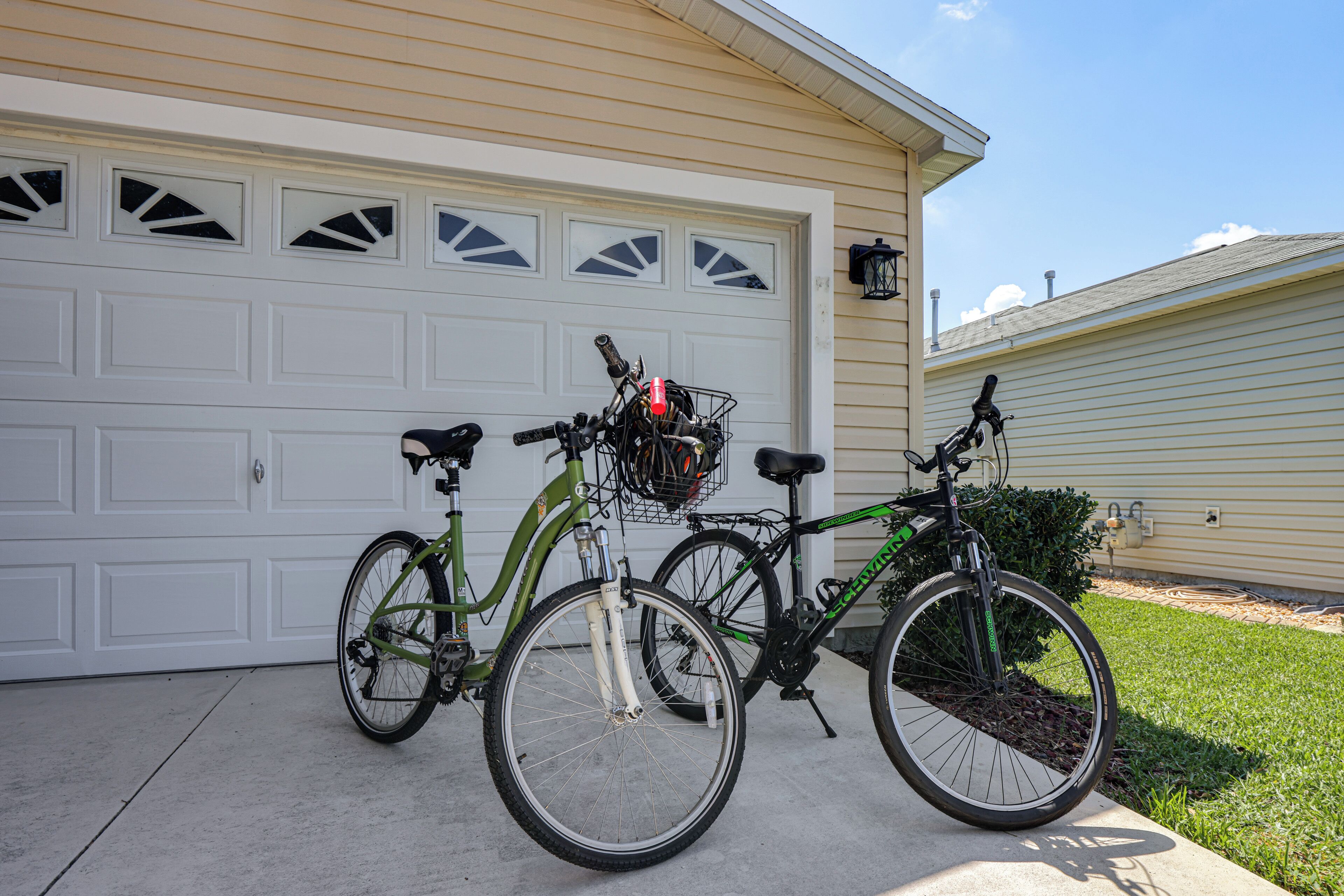 Deux vélos sont garés devant un garage dont la porte est blanche et qui possède une fenêtre ornée d’un motif en losanges.