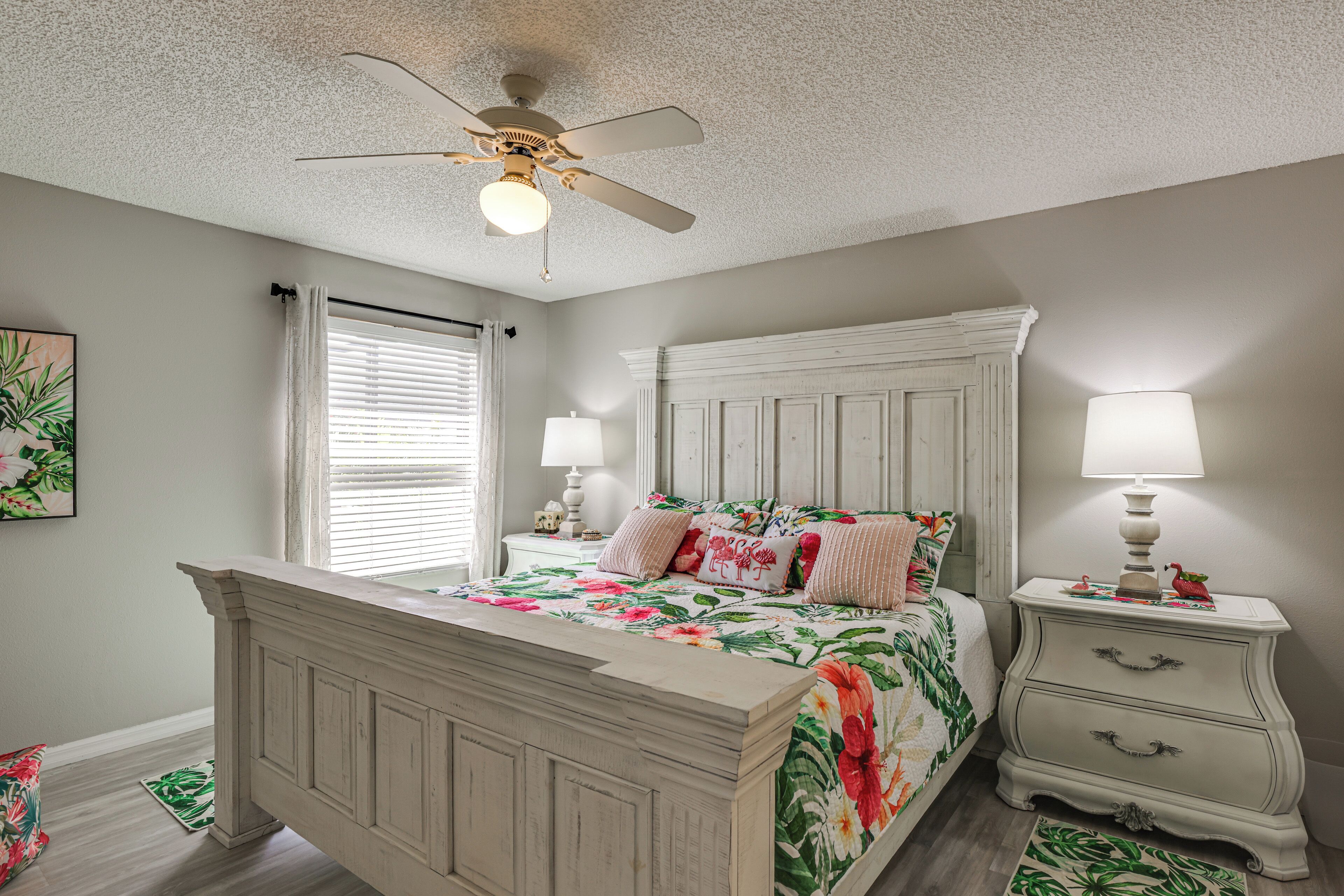 A bedroom with a bed, nightstands, a ceiling fan, and a window with blinds.