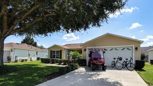 A residential driveway leading to a garage with a red golf cart parked in front. - Golf, Dine & Relax Poolside! The Villages Retreat (The Villages)