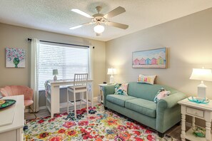 A room with a ceiling fan, a desk with a chair, a couch, and a colorful floral rug. - Golf, Dine & Relax Poolside! The Villages Retreat (The Villages)