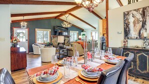 A dining area with a wooden table set for a meal, a chandelier, and a large painting on the wall. - Hike, Bike & Ski: Evergreen Home w/ Game Room! (Evergreen)