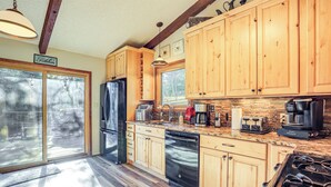 A kitchen with wooden cabinets, a stainless steel refrigerator, a dishwasher, a stove, and a window overlooking the outdoors. - Hike, Bike & Ski: Evergreen Home w/ Game Room! (Evergreen)