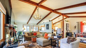 A spacious living room with a high ceiling, wooden beams, a fireplace, and a dining area. - Hike, Bike & Ski: Evergreen Home w/ Game Room! (Evergreen)