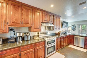 A kitchen with wooden cabinets, stainless steel appliances, granite countertops, and a built-in oven. - Beach and Skiing at Zephyr Cove House (Zephyr Cove)