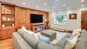 Un salon moderne doté d’un grand téléviseur à écran plat, de meubles en bois et d’un canapé d’angle gris.