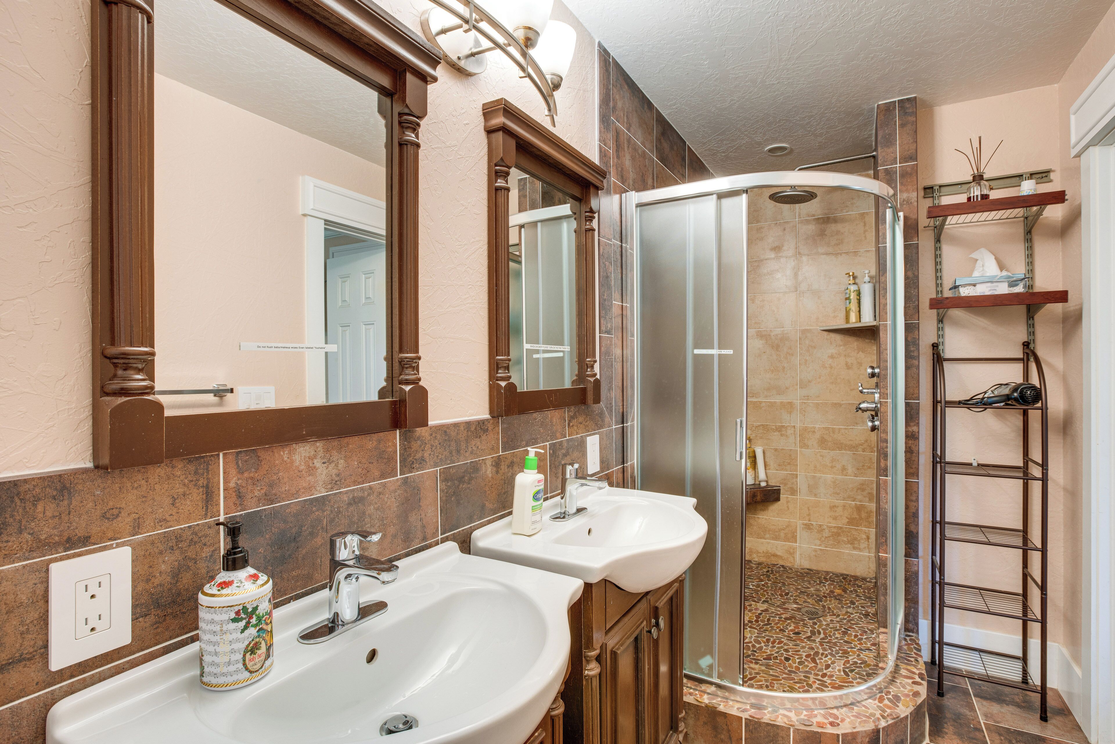Une salle de bain avec deux lavabos, une douche et un grand miroir.