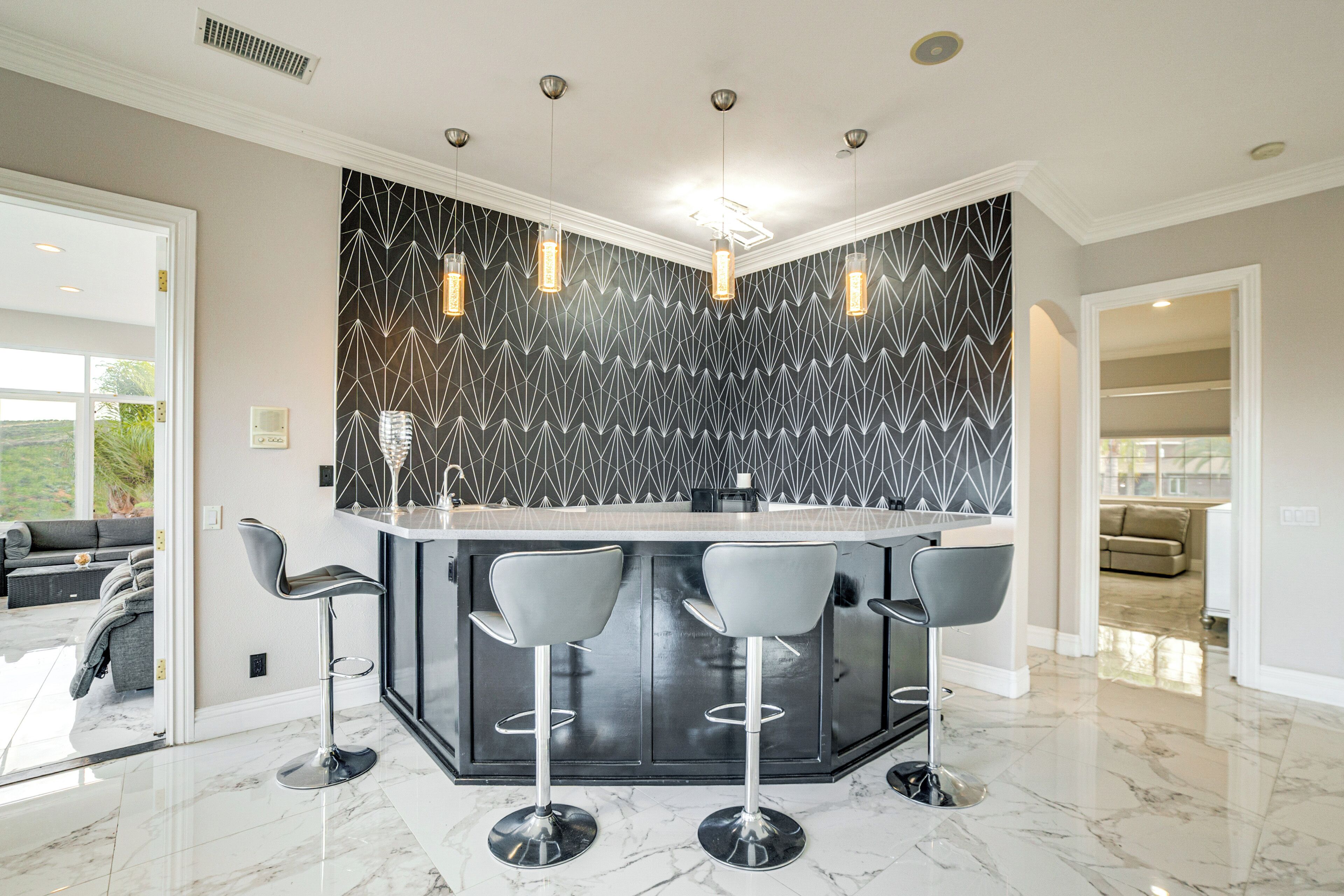 A modern kitchen with a central island, bar stools, and pendant lighting.