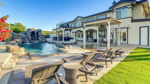A large house with a swimming pool, outdoor furniture, and a waterfall feature.