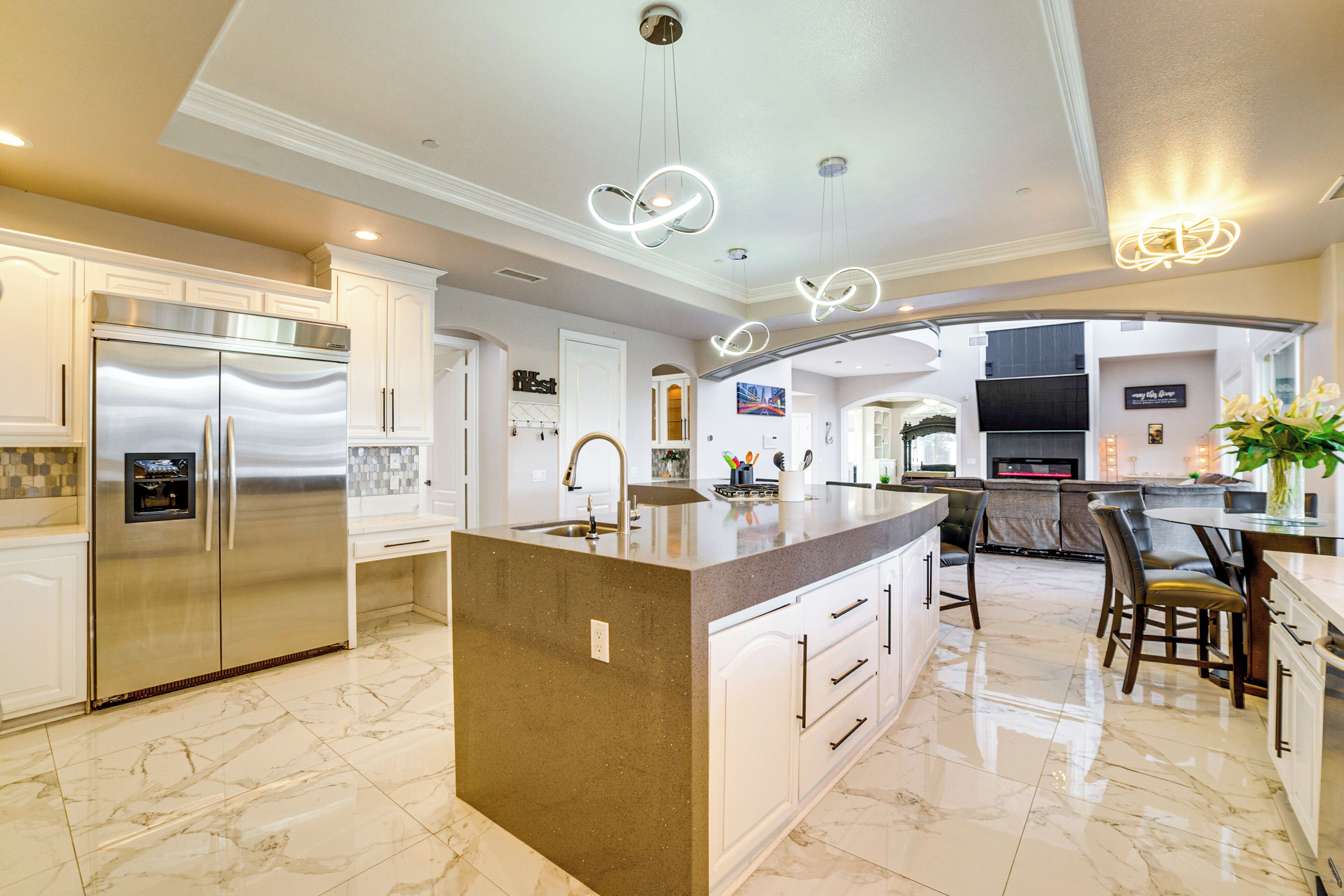 A modern kitchen with a central island, stainless steel appliances, and a dining area with a glass table and chairs.