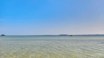 Une vue dégagée sur une mer calme, avec une terre lointaine à l’horizon et un bateau.