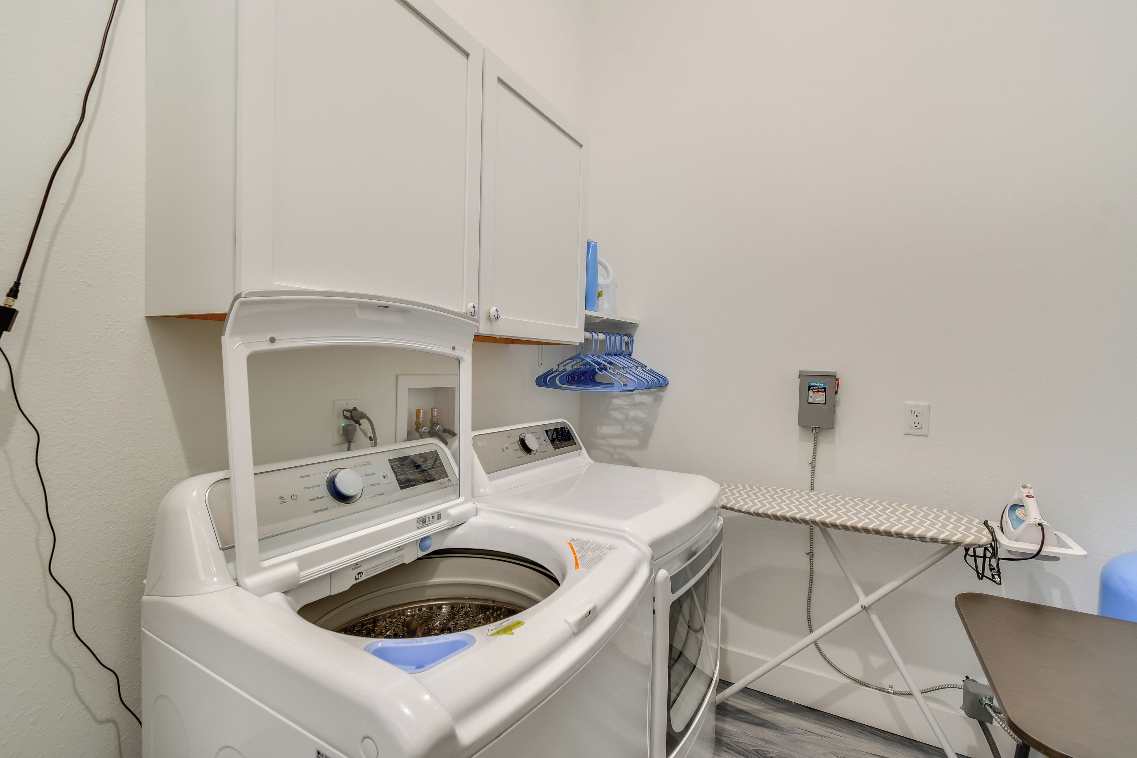 Een wasruimte met een wasmachine, een strijkijzer en een droogrek.