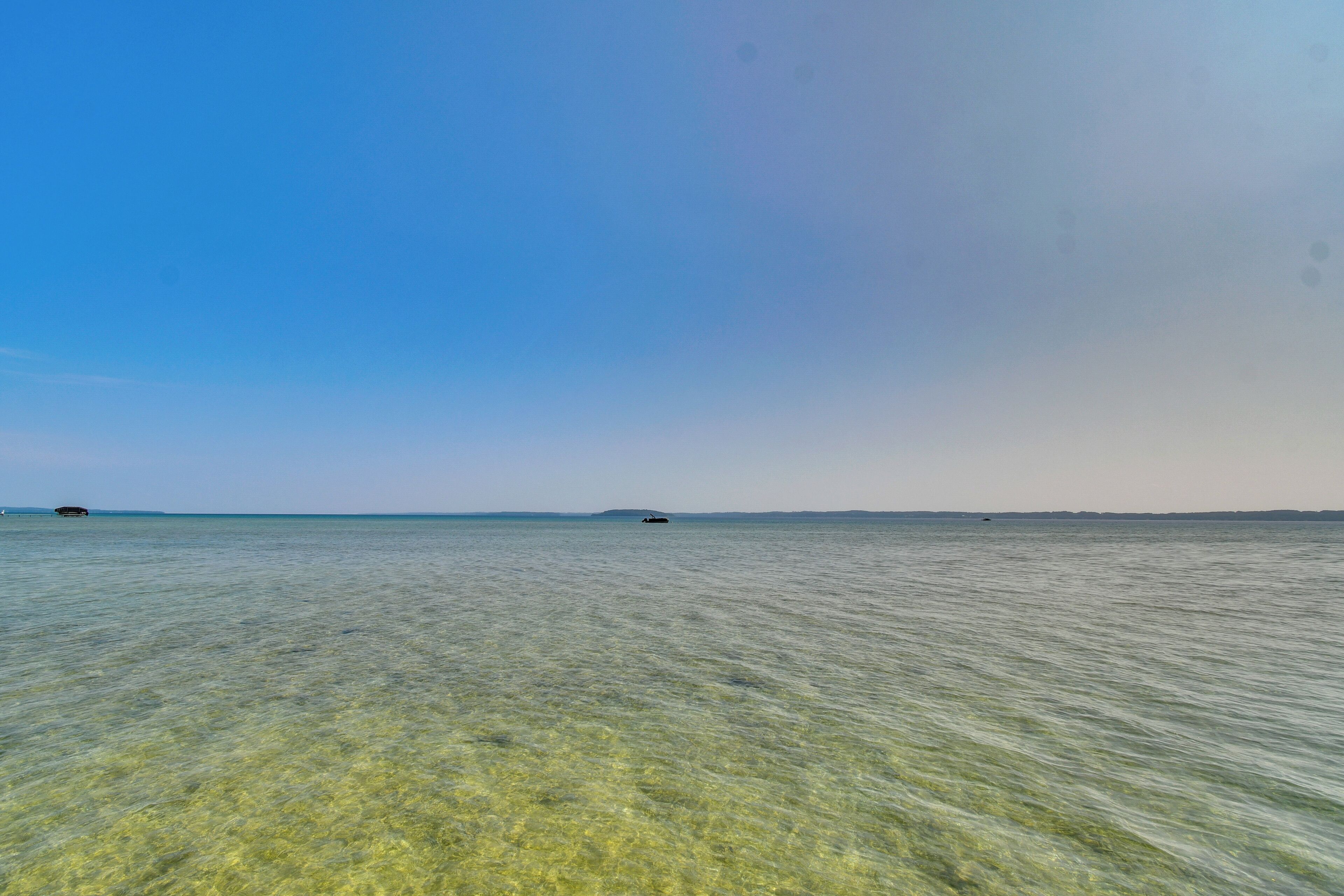 A clear view of a calm sea with a distant shoreline.