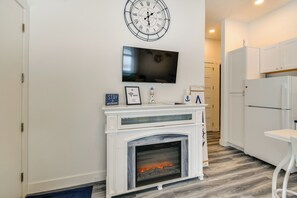 A modern kitchen with white cabinetry, a built-in fireplace, a wall-mounted TV, and a clock. - New Home on Lake Michigan's Traverse City West Bay (Traverse City)