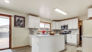 A modern kitchen with white cabinets, a central island, a microwave, and a sink. - 2 Mi to Golf Course! Family Home in Pueblo West (Pueblo)
