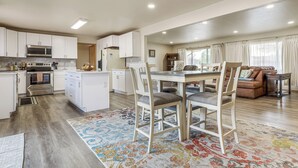 A modern kitchen with white cabinets, a microwave, and an oven. There is a dining area with a table and chairs, and a living room with a sofa and a coffee table. - 2 Mi to Golf Course! Family Home in Pueblo West (Pueblo)
