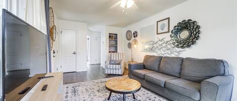 A modern living room with a grey sofa, a round coffee table, and a ceiling fan.
