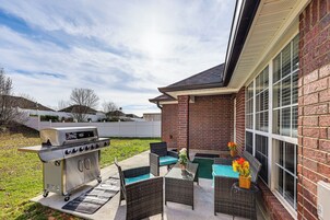 Un patio con una parrilla, muebles de mimbre y una piscina pequeña.