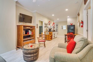 Un salon avec une bibliothèque en bois, une table basse en verre et un coussin rouge sur un canapé.