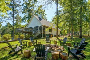 A cabin with a deck, surrounded by trees and outdoor seating. - Wilderness Retreat on Crooked Creek, Lake Sinclair (Eatonton)