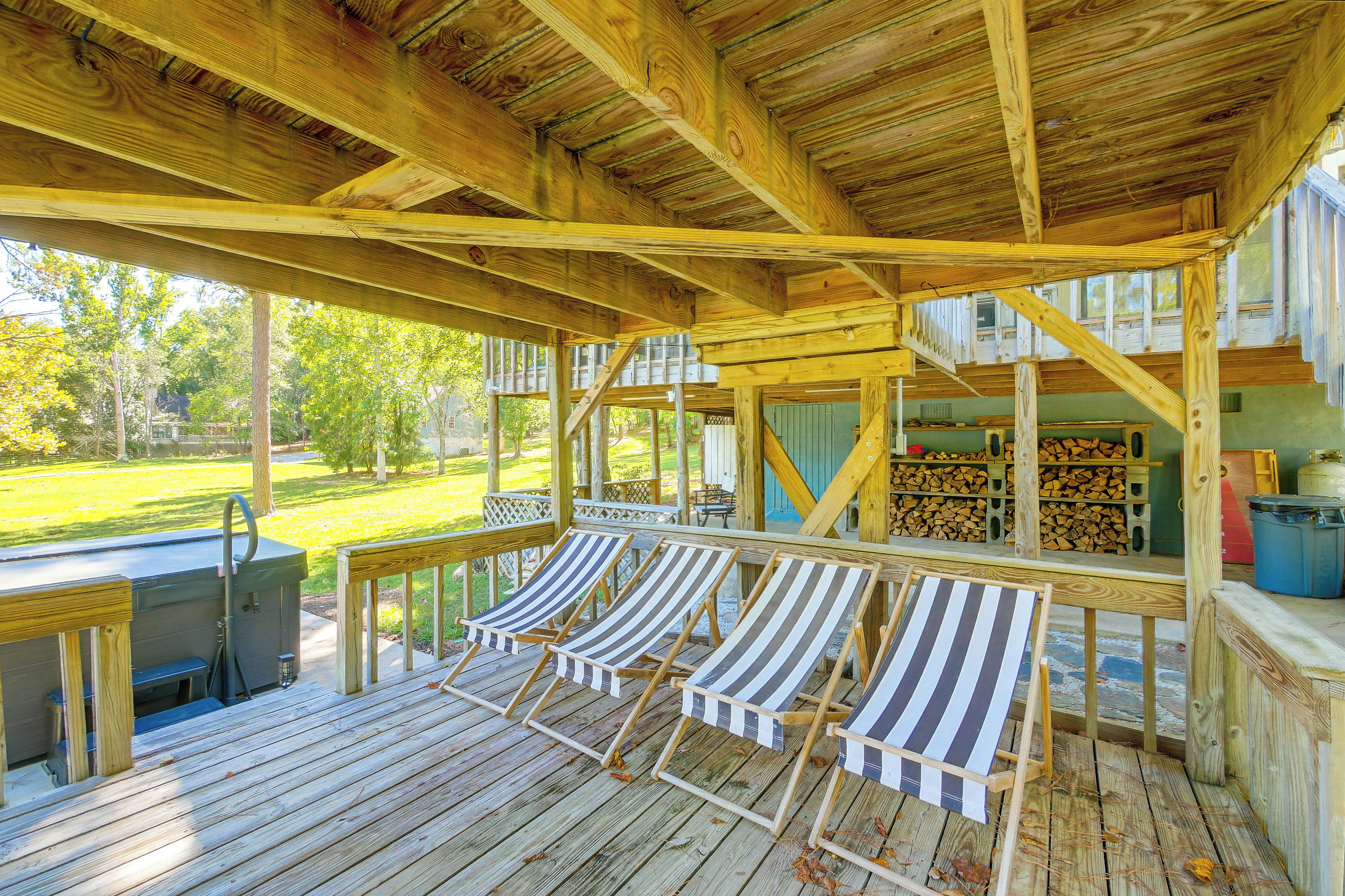 A wooden deck with lounge chairs, a grill, and a view of a grassy area.
