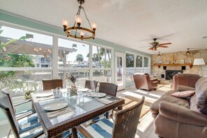 A spacious living area with a dining table set for four, surrounded by wicker furniture and a large window offering a view of the outdoors. - Fish, Paddle & Explore: Crystal River Gem w/ Dock (Crystal River)