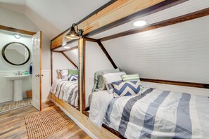 A bedroom with a wooden ceiling, a bed with striped bedding, a bedside table, and a mirror on the wall. - Anglers' Haven! Cedar Creek Reservoir Getaway (Kemp)