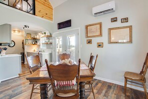 A dining area with a wooden table and chairs, a kitchen in the background, and framed pictures on the wall. - Anglers' Haven! Cedar Creek Reservoir Getaway (Kemp)