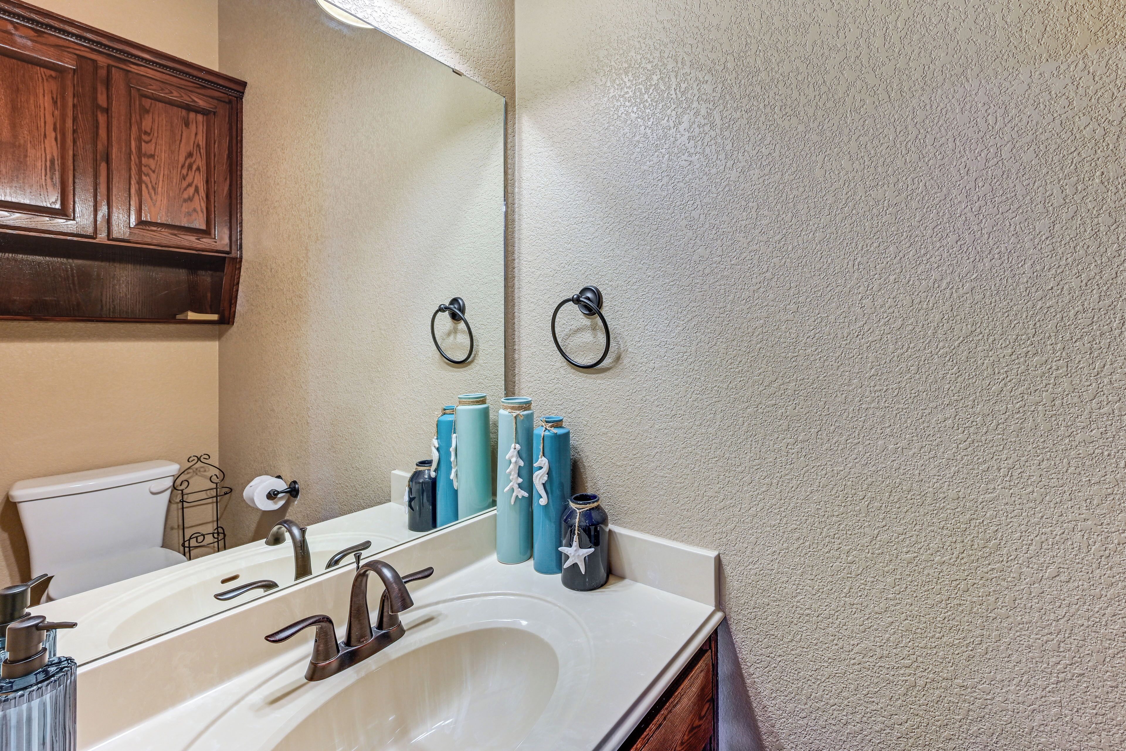 A bathroom with a white sink, a mirror, and wooden cabinets.