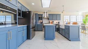 Une cuisine moderne avec des armoires bleues, des appareils en acier inoxydable et un sol en marbre.