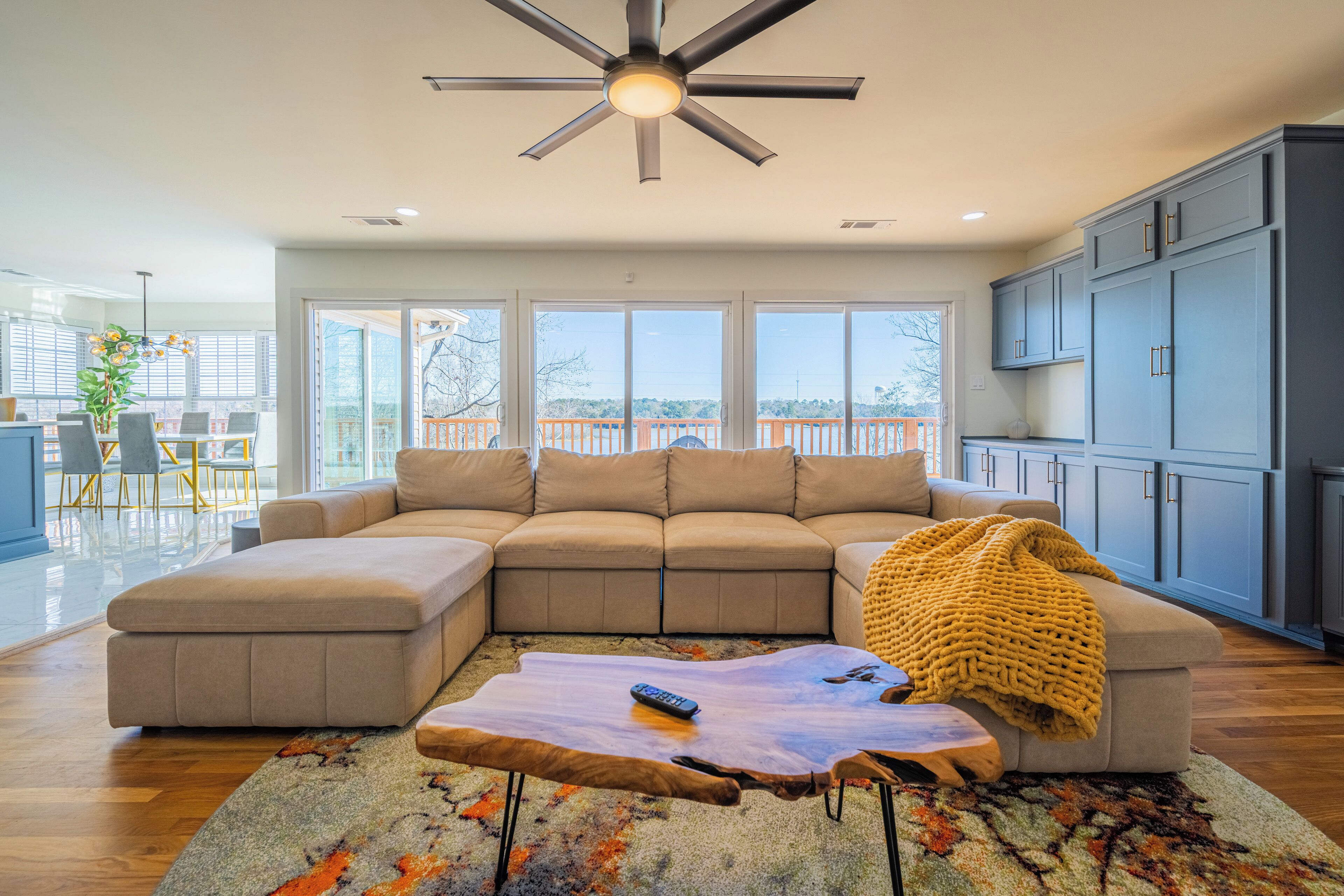 A modern living room with a sectional sofa, a coffee table, and a ceiling fan.