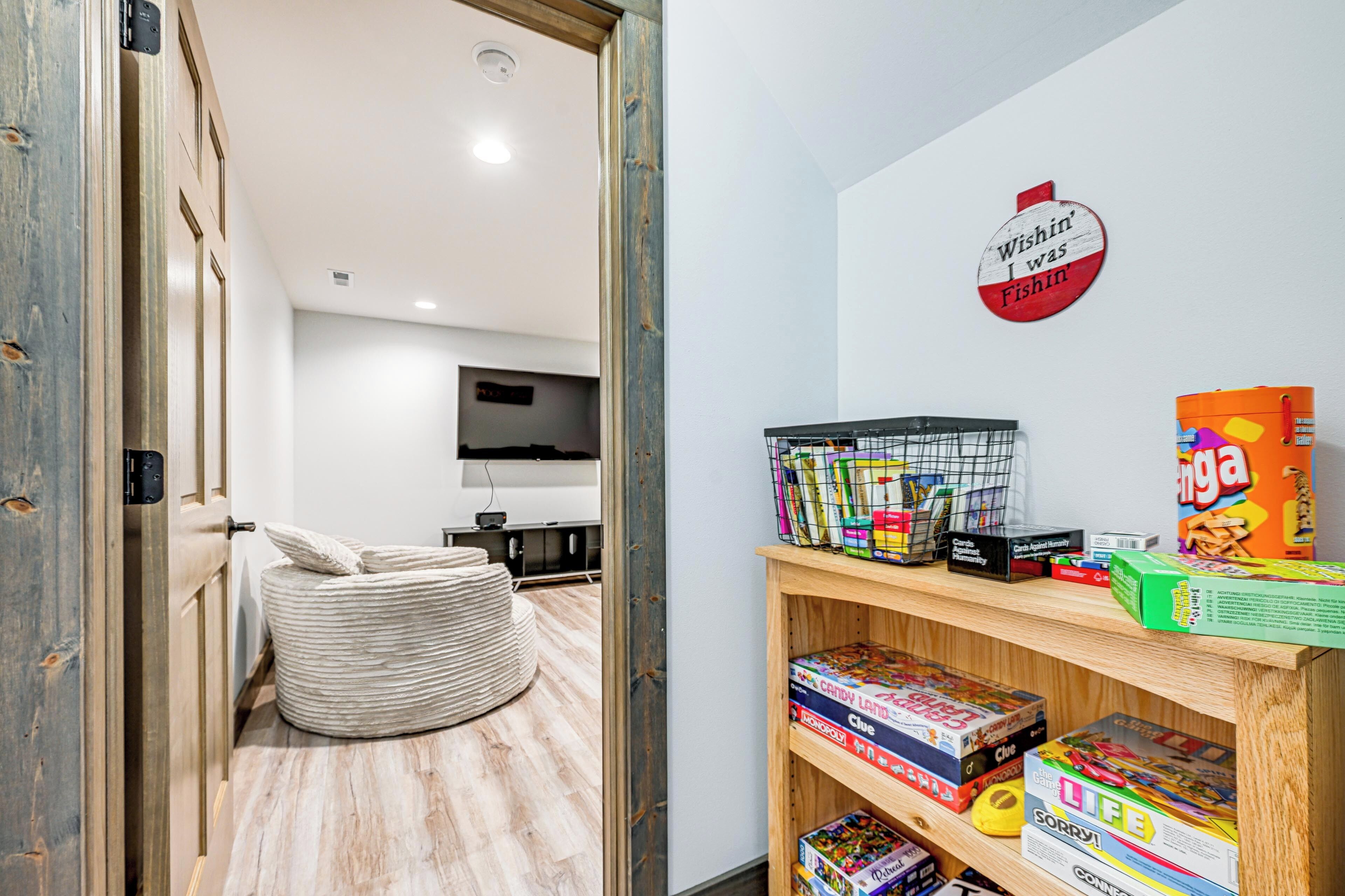 Une pièce moderne avec un plancher en bois, un fauteuil en forme de sac de haricots, une étagère remplie de jeux de société et une horloge murale.