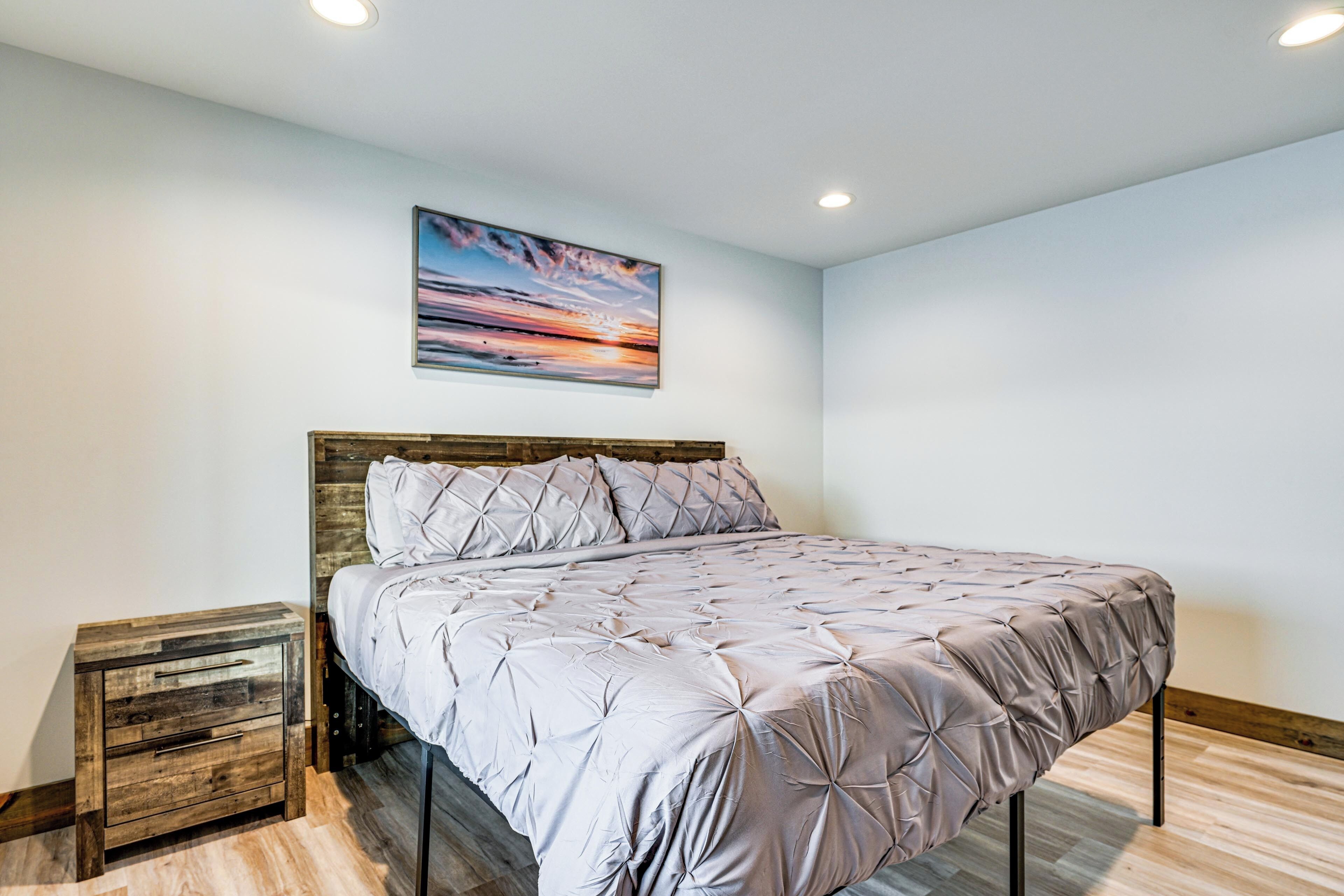A bedroom with a bed, a nightstand, and a painting on the wall.