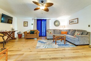 A living room with a ceiling fan, a sofa, a chair, a coffee table, and a rug.