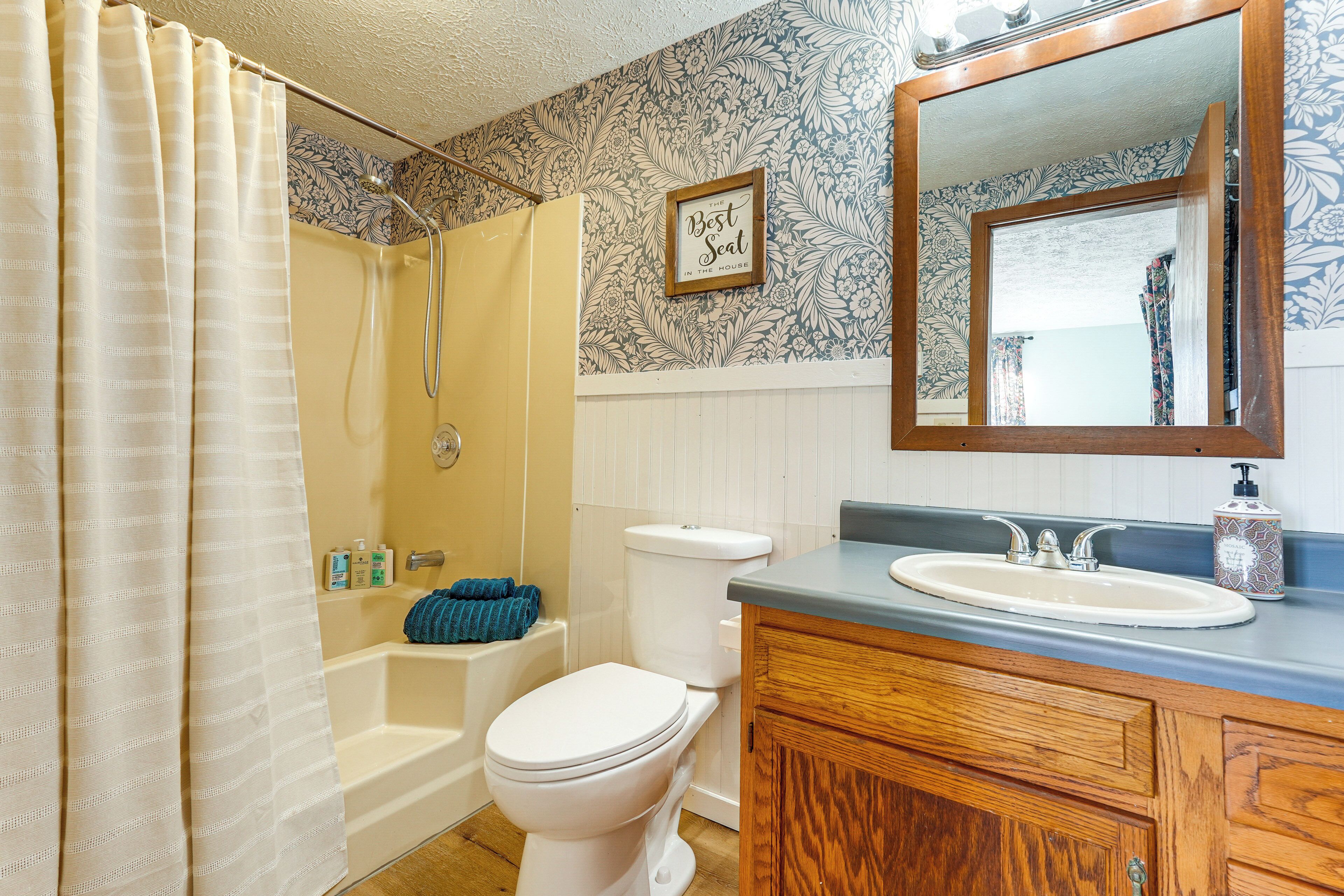 A bathroom with a bathtub, toilet, sink, and mirror.
