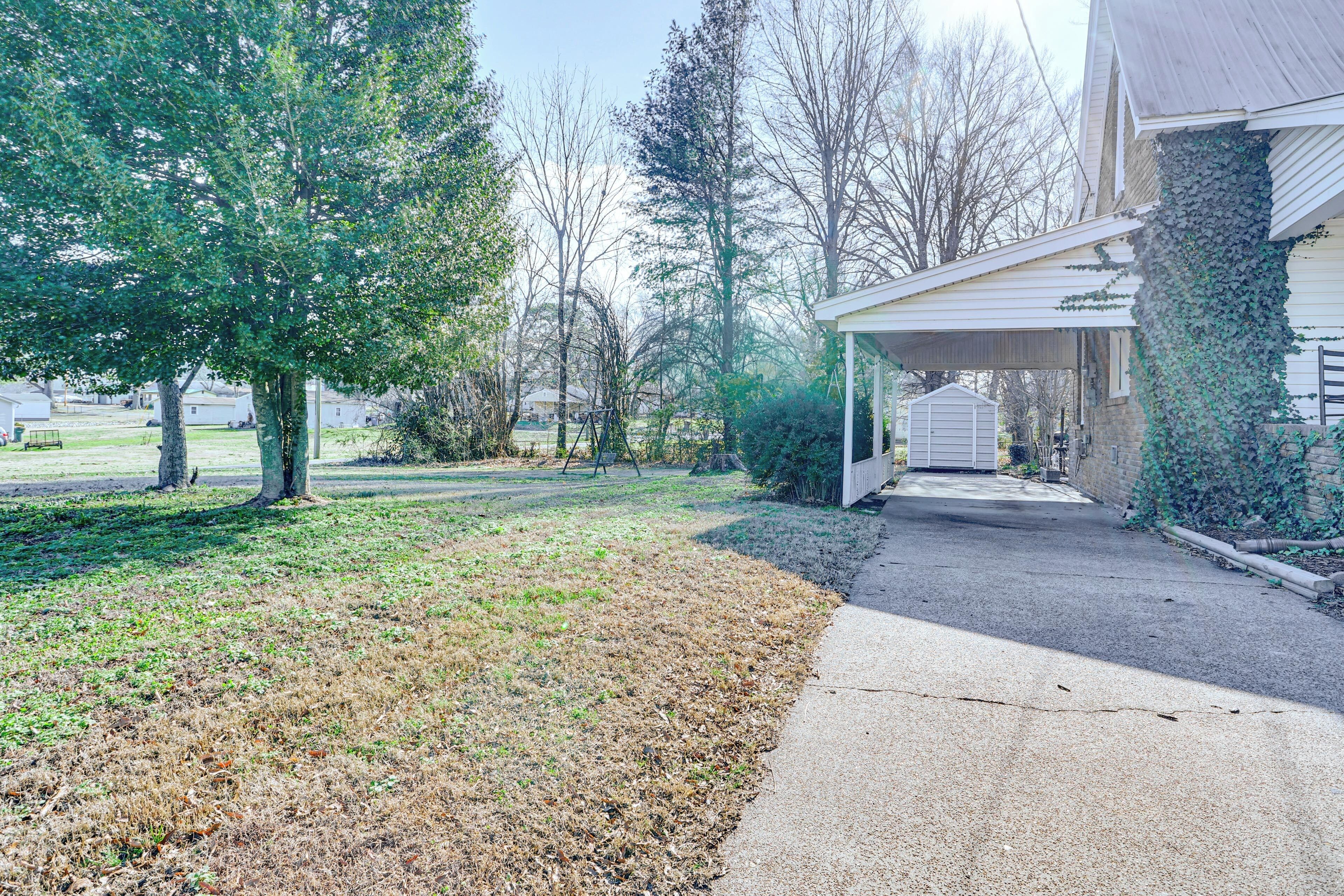 A residential property with a covered porch, a grassy yard, and a driveway leading to a garage.